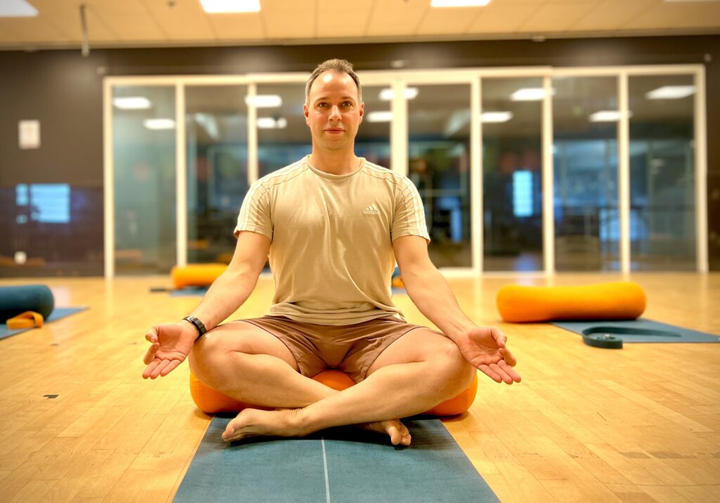 Image of a man in a lotus yoga pose in a fitness studio